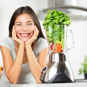 your women next to blender with veggies inside
