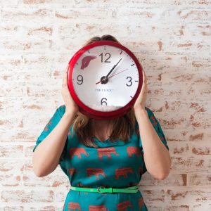 women standing holding clock over face