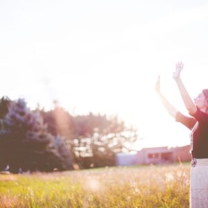 facing face to the sun woman arms out in sunshine in field